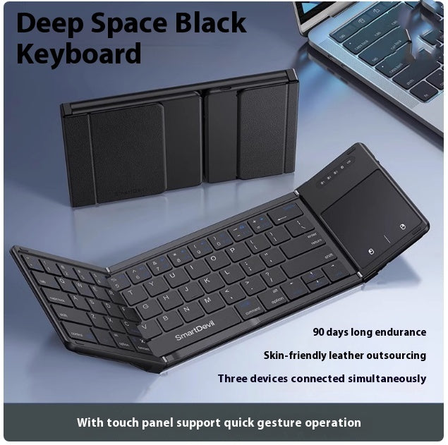 Black folding Bluetooth keyboard with touchpad and foldable design next to laptop