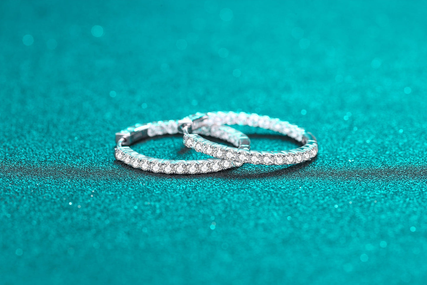 Fashion sterling silver earrings for women with sparkling stones on turquoise background